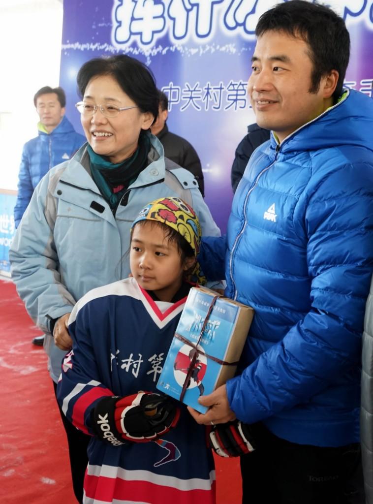 新华社照片，北京，2015年12月26日(体育)（1）冰球——中小学生冰球运动有了新教材12月26日，一名冰球小选手手捧《冰球校本指导教材》与嘉宾合影。当日，北京市中关村三小联合万水