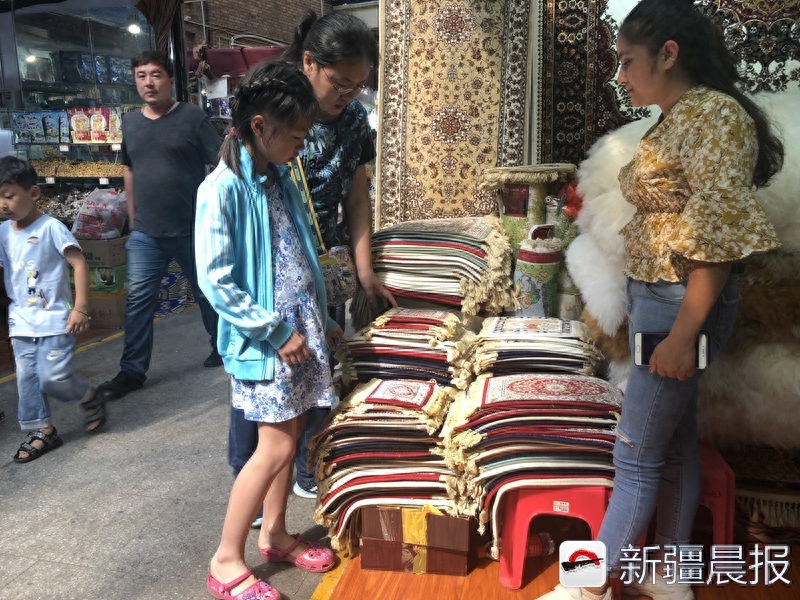 新疆晨报讯（文/图/记者 阿丽亚.阿里木）8月30日在新疆国际大巴扎开新疆挂毯店的阿孜古丽格外忙碌。“沙发座垫有一米七的，也有一米五的，手工做的也有机器做的。价格不一样。”