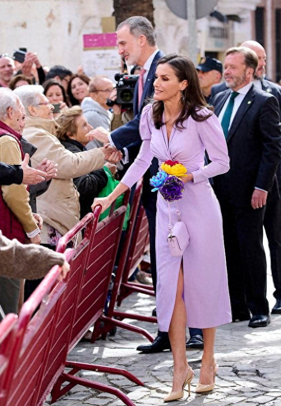西班牙王后又开始美了，最新造型穿着香芋紫连衣裙，V领口设计还是开叉款式，大冷天的走在室外与民众互动，脚上穿着的还是凉鞋，一身色彩鲜艳的造型很是漂亮，就是看着让人都冷